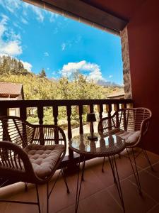 a balcony with chairs and a table and a window at Apartamento Acogedor con Vistas Espectaculares en Liébana, Picos de Europa in Camaleño