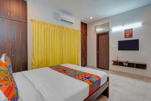 班加罗尔FabHotel Jeevith Garden Residency - Kundalahalli, Brookefield的卧室里有一张床和一台电视机