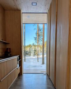 una cucina con una porta aperta su una foresta di Hideout Villa Salmi a Säräisniemi