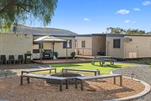 a patio with two picnic tables and a fire pit at Alice Village in Alice Springs