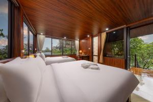 a bedroom with two white beds and large windows at Tam Coc Eco Field Nest By ANMS GROUP in Ninh Binh