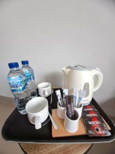 a tray with a tea kettle and cups and water at The Green Sidemen in Silebeng