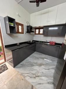 a kitchen with black counters and white cabinets at Udupi Coral Homestay in Kalyānpur