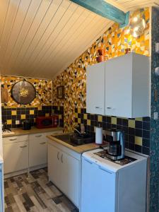 a kitchen with white cabinets and black and yellow tiles at Chalet de campagne en Dordogne avec piscine in Saint Agne