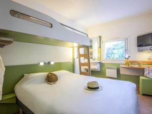 a hotel room with a bed with a hat on it at ibis budget Antibes Sophia Antipolis in Vallauris