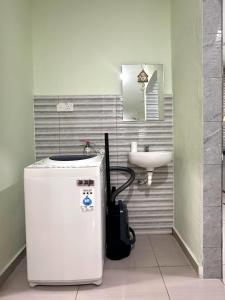 a small bathroom with a sink and a refrigerator at Specious Living Cozy House in Bukit Mertajam