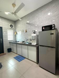 a kitchen with a refrigerator and a microwave at Specious Living Cozy House in Bukit Mertajam