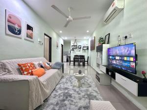 a living room with a couch and a flat screen tv at Specious Living Cozy House in Bukit Mertajam