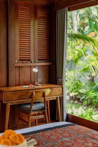 un escritorio de madera con una silla junto a una ventana en Sang Mong Ubud, en Ubud