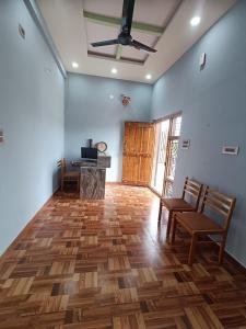 a living room with wooden floors and a ceiling fan at NANDANAVANA Homestay in New Hampi
