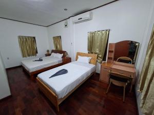 a bedroom with two beds and a desk and a mirror at Twin House in Luang Prabang