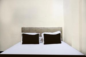 a white bed with two black pillows on it at Hotel O Medan near Sun Plaza formerly Medan Baru House in Medan