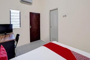 a bedroom with a bed and a desk and a door at Hotel O Wonoayu Residence Syariah in Sidoarjo +76 photos