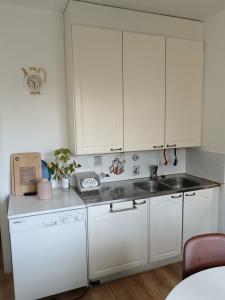 Una cocina con gabinetes blancos y un fregadero. en Tilava kaksio Jussilankadulla, en Hyvinkää