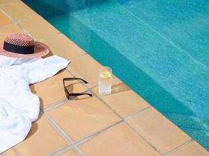 Un sombrero y un vaso de agua junto a una piscina. en Ibis Budget Hyères, en Hyères