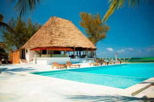 a resort with a swimming pool and a thatch hut at 1Zi Beachfront Resort in Paje