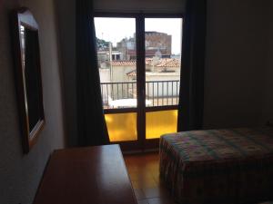 a room with a window with a view of a balcony at Pensión Juan Ramón in Lloret de Mar