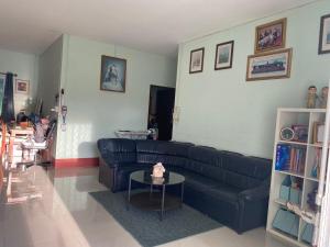 a living room with a black couch and a table at Garden house in Ban Krok Khi Nu