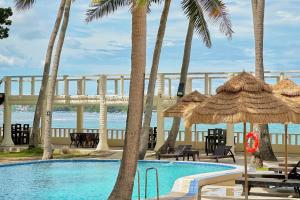 a swimming pool with palm trees and a bridge at Mandala Beach Resorts powered by Cocotel in Bitangan