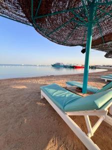 uma praia com duas espreguiçadeiras e um guarda-sol em Porto View Touristic Center em Hurghada