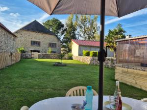 a table with an umbrella in a yard at Jolie maison de campagne avec spa en option in Rauville-la-Place