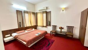 a bedroom with a bed and a table and chairs at Hotel Mahendra, Karad in Karad +12 photos