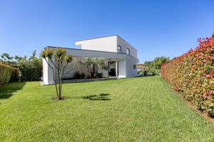 a white house with a green yard at Contemporary Villa Nada with Pool and Sauna in Tinjan