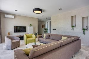 a living room with a couch and chairs and a tv at Contemporary Villa Nada with Pool and Sauna in Tinjan