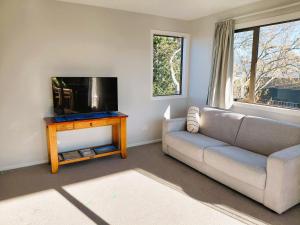 a living room with a couch and a flat screen tv at Motueka by the sea in Motueka