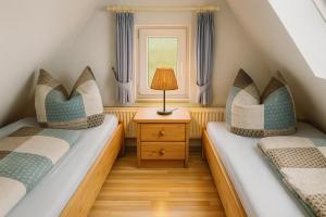 two beds in a small room with a lamp on a table at Lüttjes Diekhuus in Butjadingen OT Tossens