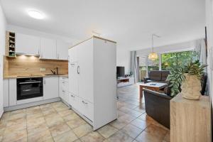 a kitchen with white cabinets and a living room at Ferienwohnung Seehase in Hooksiel