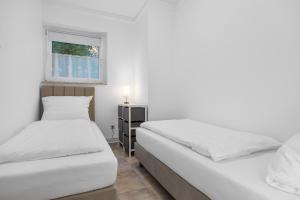 two beds in a white room with a window at Ferienwohnung Seehase in Hooksiel