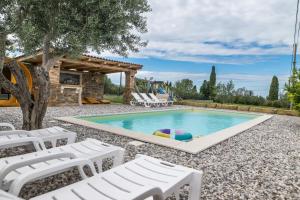 a swimming pool with white lounge chairs and a house at Villa Izola in Izola
