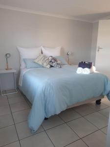 a bed with a blue blanket and pillows on it at Kom ma nader in Velddrif