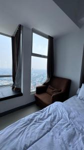 a bedroom with a bed and a chair and a window at Apartemen Anderson pakuwon mall Luxury Studio Apartment Connecting Mall, Pool & City View 37B in Surabaya