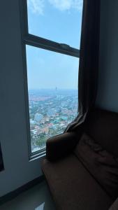a couch sitting in front of a large window at Apartemen Anderson pakuwon mall Luxury Studio Apartment Connecting Mall, Pool & City View 37B in Surabaya +1 photo