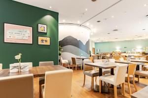 ein Restaurant mit Tischen und Stühlen und einer grünen Wand in der Unterkunft Garner Hotel Dusseldorf - Main Station by IHG in Düsseldorf