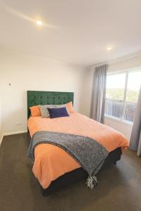 a bedroom with a large bed with an orange blanket at Driftwood House in Foxton Beach