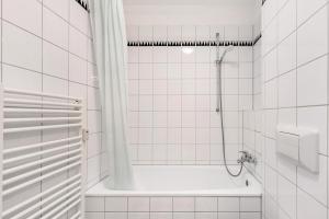 a white tiled bathroom with a shower and a tub at Albrechtshof Apartment 3 in Neu Fahrland +19 photos