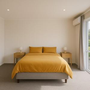 a bedroom with a bed with a yellow blanket at Driftwood House in Foxton Beach