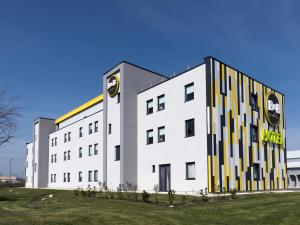 un bâtiment blanc avec un panneau sur son côté dans l'établissement B&B HOTEL Niort Marais Poitevin, à Niort