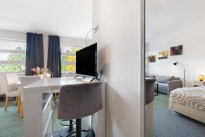 a room with a desk with a computer and a bedroom at Studio-Apartment in Neu Fahrland