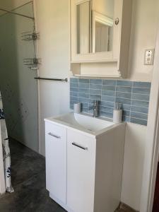 une salle de bain avec un lavabo blanc et un miroir dans l'établissement The Beach Cottage - close to beach and river mouth, à Guilderton