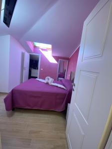 Un dormitorio con una cama morada en una habitación rosa. en Hotel Flaminia Rooms, en Roma