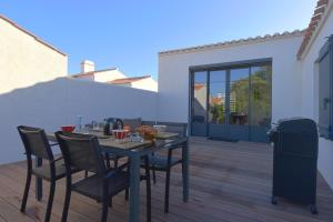 einen schwarzen Tisch und Stühle auf einer Holzterrasse in der Unterkunft Plage à 400 m - Maison pour 4 avec terrasse in La Guérinière + 12 Fotos