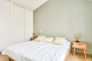 ein Schlafzimmer mit einem großen weißen Bett mit zwei Lampen in der Unterkunft Plage à 400 m - Maison pour 4 avec terrasse in La Guérinière