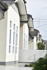 a row of white houses with a white fence at Khwanlom House in Lampang