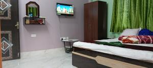 a bedroom with a bed with a tv on the wall at Sandhyamalati Homestay and Picnic Ground 
