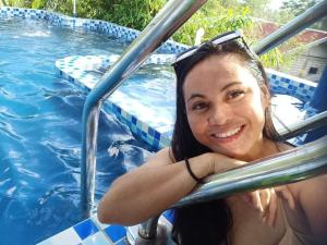 a woman in a pool with a smile on her face at Mischa Hostel in Dauis