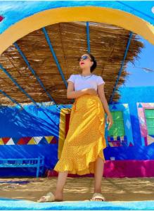a woman in a yellow dress standing on a beach at Nubian Hostel in Aswân Reservoir Colony